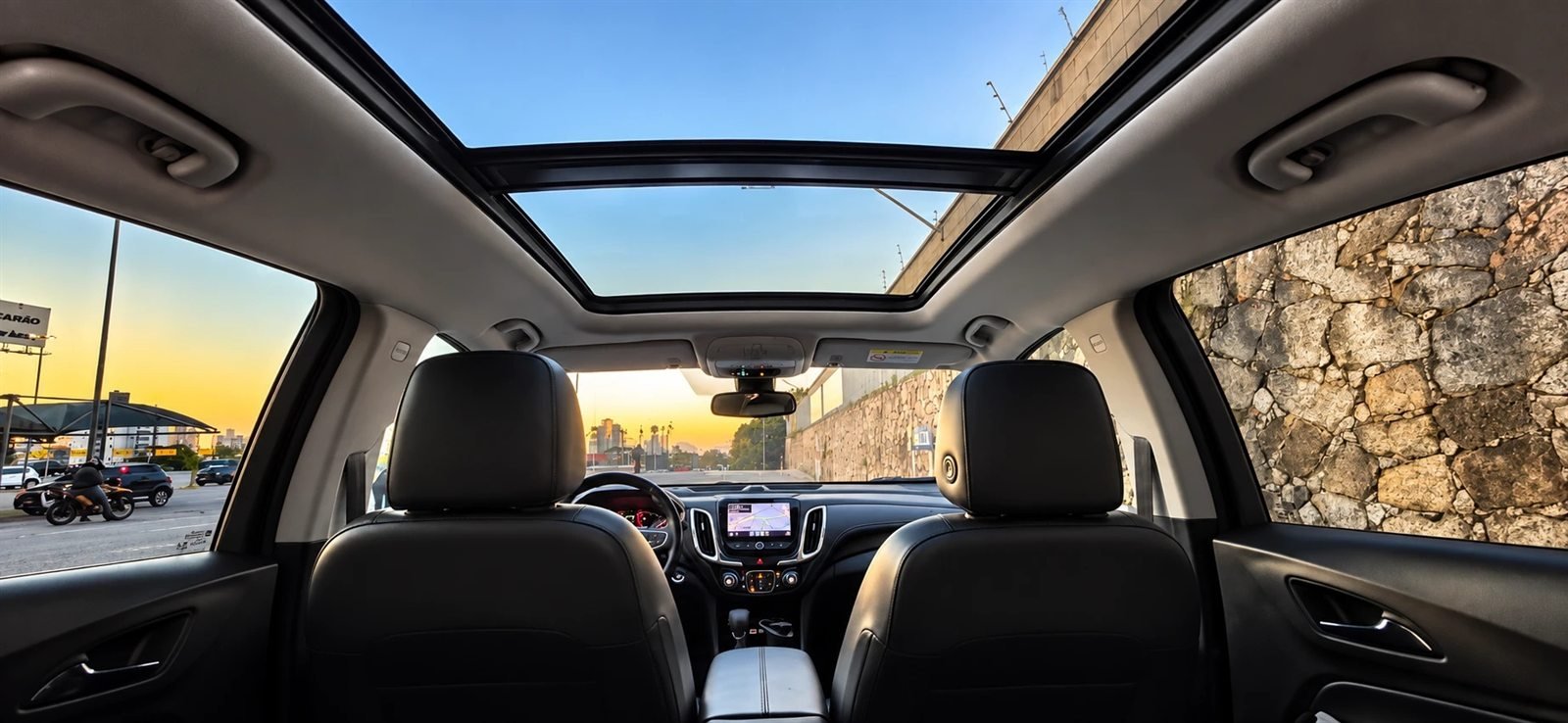 Interior de veículo com teto solar panorâmico ao entardecer